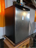 Front view of Danby Designer bar fridge showing stainless steel door and attached label.