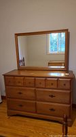 Front view of six drawer wood dresser with attached mirror on top, showing condition and knob details