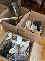 Boxes filled with assorted glass vases, mugs, bowls, coffee pots, and other kitchenware items.