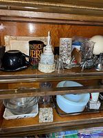 Wide view of two wooden shelves behind glass doors with various decorative and dishware items arranged on them