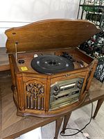 Top open view showing wooden cabinet and vinyl turntable with tonearm and platter.