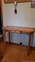 Front view of the wooden hall table showing the single drawer and tapered legs.
