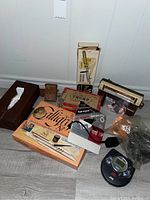 Photo showing an assortment of vintage radios, a calligraphy set, an electric engraver, JVC CD player with headphones, and other accessories on the floor.