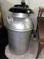 Photo of the entire milk can showing silver bottom, black top, embossed 'TRENTON DAIRY' text, and handles.