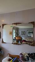 Full view of large curved wall mirror showing ornate gold tone trim and room reflection