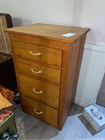 Front view of oak wood cabinet showing four drawers with curved handles and wood grain finish.