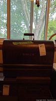 Front view of the Singer sewing machine in wood carrying case with Singer logo visible, showing the size label taped on top.