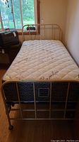 Front view of assembled beige metal twin bedframe with mattress