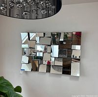 Front view of rectangular 3D accent wall mirror showing multiple reflective panels in geometric layout on wall.