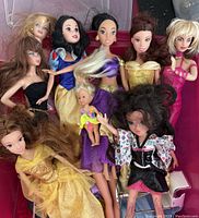 15 dolls including Barbie and baby dolls with various clothes and accessories in a pink tub, dolls range approximately 11 and 5 inches tall, some dolls show wear and need cleaning.