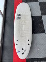 Top-down view of the full surfboard showing overall condition and shape. Visible dirt and use marks on surface. Four fin plugs and leash plug visible on tail.