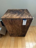 Front and side view of the square furry cowhide end table showing stud-tacked edges and mottled brown and black coloring.