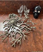 Metal coral-shaped decorative basket with branch details, and black skull candle with red eyes on rust-colored surface