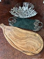 All four items shown: wooden marble-look cheeseboard, green marble cheeseboard with metal grapevine handles, glass bowl, and metal leaf decorative bowl base.