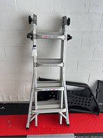 Front view of the folded aluminum Gorilla ladder showing rungs and wheels at top.