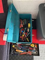 Overview of blue toolbox open showing assortment of hand tools inside and black removable tool tray in front filled with additional hand tools.