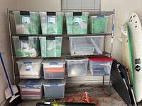 Front view of metal shelving rack loaded with plastic storage containers and tools. Showcases overall structure and usage context.