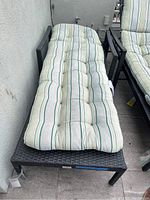 Wicker patio lounge chair with metal frame and striped cushion, showing full chair and cushion for reclining use.