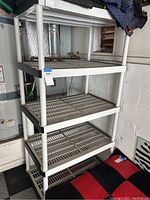 Plastic rack shelf with four slotted shelves and sturdy cylindrical legs.