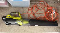 Side angle view of Ryobi handheld electric blower with attached orange extension cord