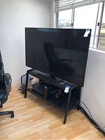 Front view of Samsung TV on black metal stand near window