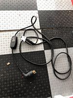 Full view of Tesla charger cable with plug and charging unit laid on patterned floor.