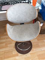 Front view of the wood and fabric swivel bar chair showing curved backrest and seat with grey fabric covering.