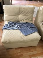 Front view of beige leather armless chair with a grey cloth draped on seat