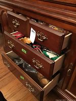 Three partially open drawers filled with various holiday and household items including napkins, utensils, candles, and glass containers.
