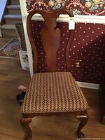 Full view of one wooden dining chair with curved backrest and patterned fabric seat.