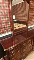 Wide front view showing dresser top surface and mirror reflecting plaid wallpaper in background.