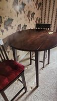 Photo of the drop leaf pub height table and one chair with maroon cushion.