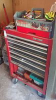 Full view of the red Craftsman steel toolbox on wheels with the red plastic Tote Caddy filled with hand tools on top.