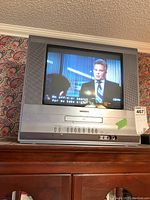 Front view of Toshiba CRT TV showing screen, control buttons, and DVD player slot.