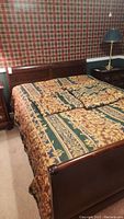 Full view of wooden bed frame with headboard and mattress with patterned linens.
