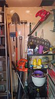 Two handheld leaf blowers mounted and on floor with garden pots and metal plant stand panels on shelves