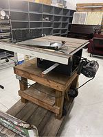 Side angle shot of the Craftsman 10-inch table saw showing the metal table, circular saw blade, motor, and wooden wheeled stand.