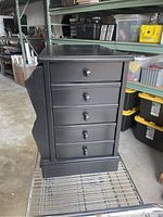 Front view of black wooden end table showing five drawers and side magazine rack.