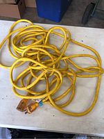 Full view of the coiled yellow heavy duty extension cord on a table.