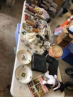 Wide view of the table showing the arrangement of various vintage items including John Deere plates, jewelry, plush toy, basket and book titled 'Railways'.