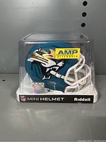 Mini helmet front and side view showing Jaguars logo, signatures, and display case with Riddell and NFL branding.