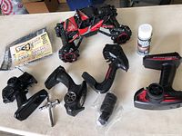 Overview of RC car with four remote controls, belts, bottle, and extra tires on a table
