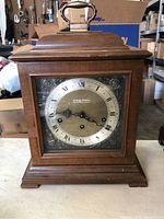 Front view of Seth Thomas mantle clock showing wooden case, ornate silver-tone dial with roman numerals, and brass handle on top