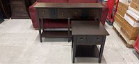 Wide shot showing both the sofa table and end table side by side on a concrete floor, highlighting their dark wood finish and drawer design.