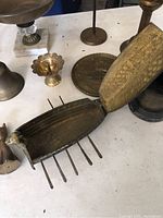 Photo of a boat-shaped brass container with spikes and hinged lid alongside other brass items on a table.