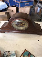 Full view of the vintage wooden mantel clock showing its curved shape and dark brown wood finish.