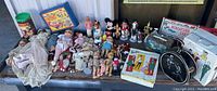 Overview of the collection of vintage dolls, toy cases, and other vintage toys arranged on a table, showing worn and dirty condition.