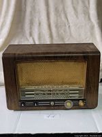 Front view of the vintage Philips Model 725 tube radio showing the wooden case, gold mesh speaker grille, tuning scale, and knobs.