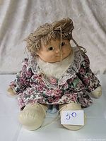 Front view of the vintage Jesmar Cabbage Patch Kid doll showing facial features, yarn hair and floral dress with lace collar.