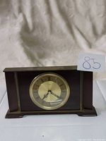 Front view of vintage Metamec mantel clock showing round clock face with mixed Roman and Arabic numerals and dark wood case.